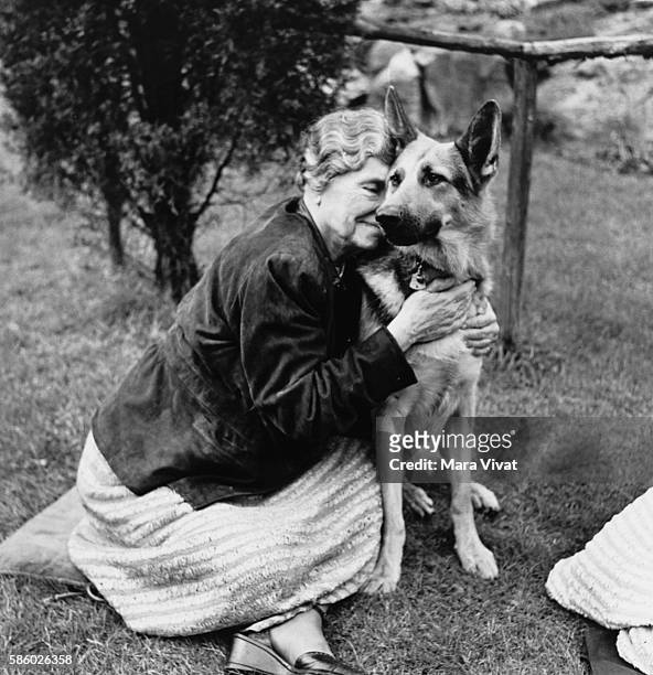 Teacher and author Helen Keller hugs her German shepherd on a garden lawn. Keller achieved wide recognition by overcoming blindness and deafness to...