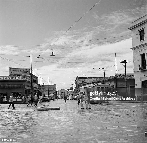 Street view of a cable car as men walking across the street in Havana, Cuba.