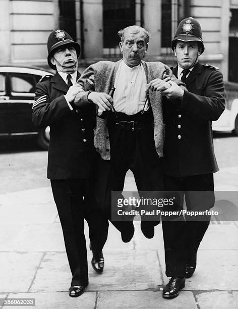 Actor Larry Noble is lead away by actors Leo Franklyn and Brian Rix dressed as policeman, during rehearsals for the comedy play 'A Policeman's Lot'...