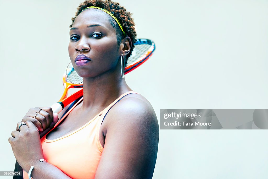 Sports woman in gym clothes with tennis racket