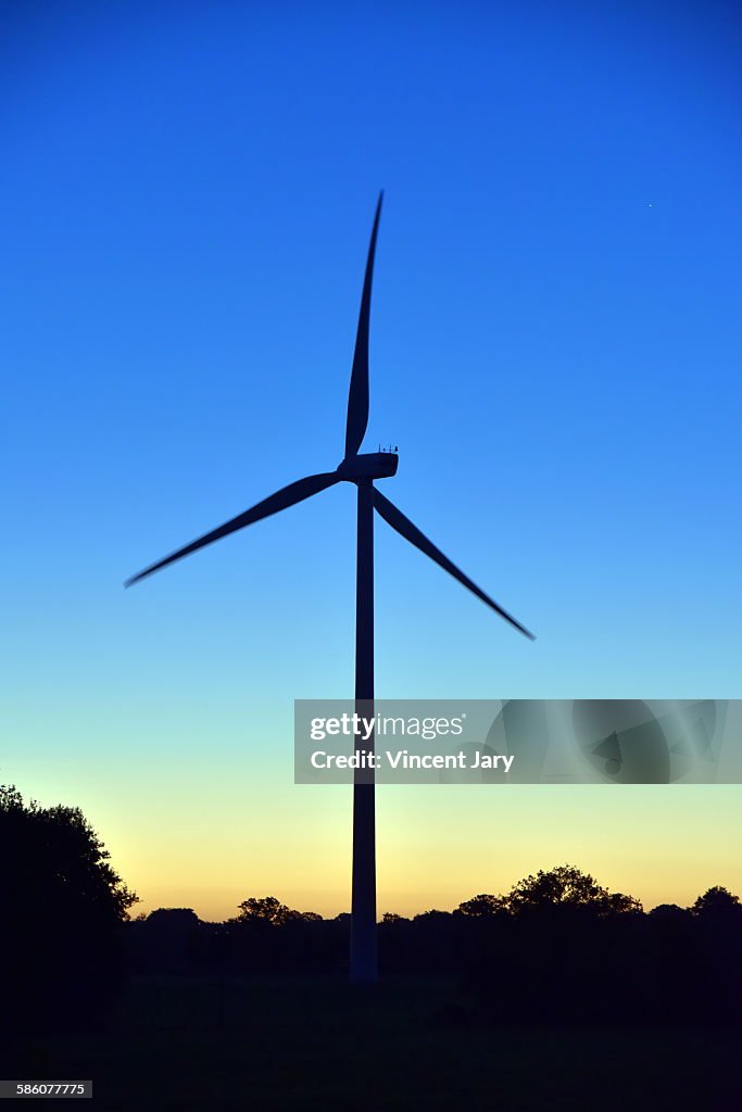 Sunrise with wind turbine at combourg france