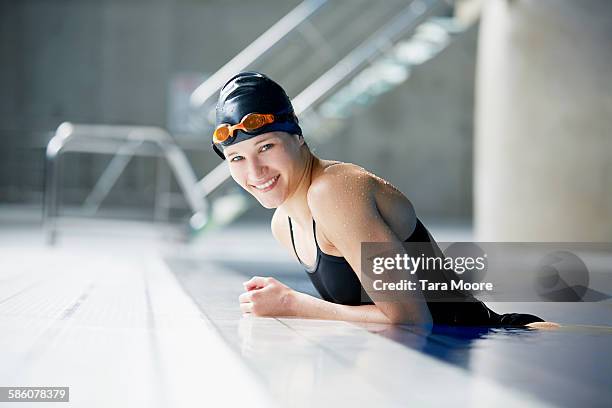 female swimmer smiling to camera in pool - gorro-de-baño fotografías e imágenes de stock