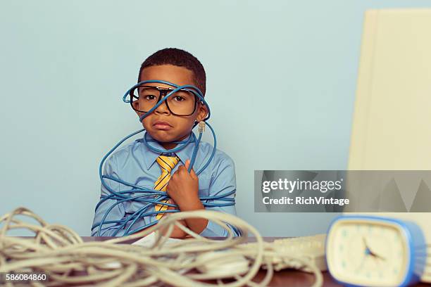 young boy it professional frowns at computer with wire - electrical overload stockfoto's en -beelden