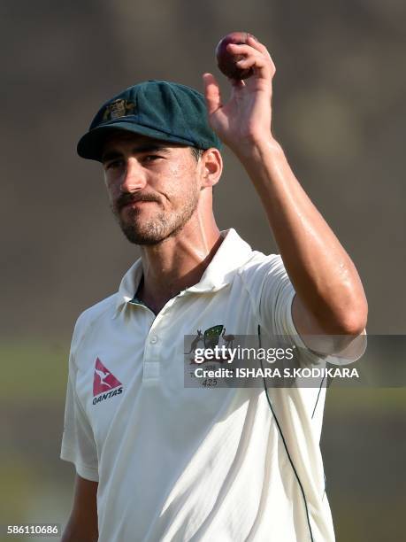 Australian cricketer Mitchell Starc holds the ball as he celebrates taking a five wicket haul while walking back to the pavilion at the end of the...