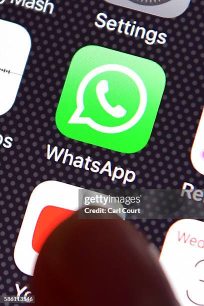 Persons finger is posed next to the Whatsapp app logo on an iPhone on August 3, 2016 in London, England.