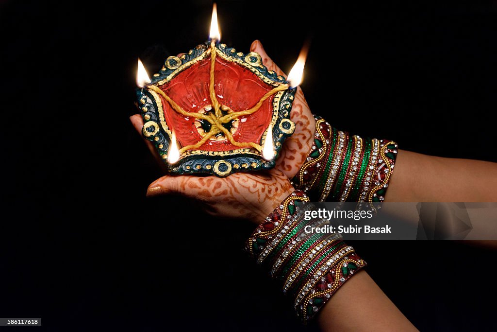 Woman with lit earthen lamp at Diwali festival,India.