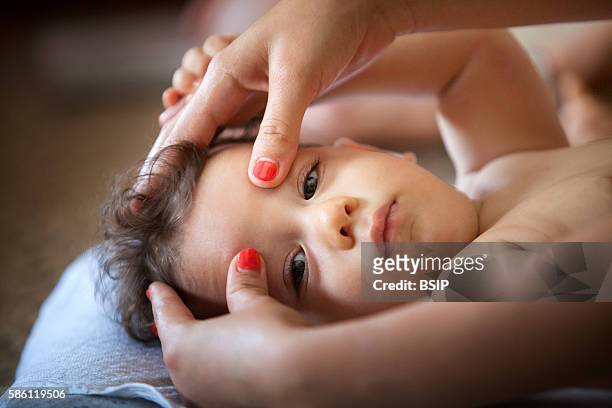 Baby massage lesson with a certified masseur, a young mother learns how to massage her 1-year old son.