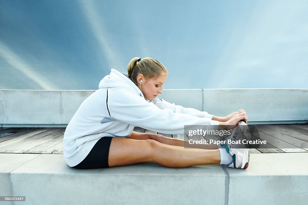 Lady stretching her legs and listening to music