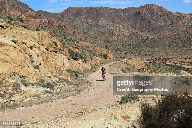 Person cycling in Cabo de Gata national park, Monsul, near San Jos, Almeria, Spain.