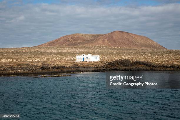 Isolated whitewashed house and Agujas Grandes volcano, La Isla Graciosa, Lanzarote, Canary Islands, Spain.