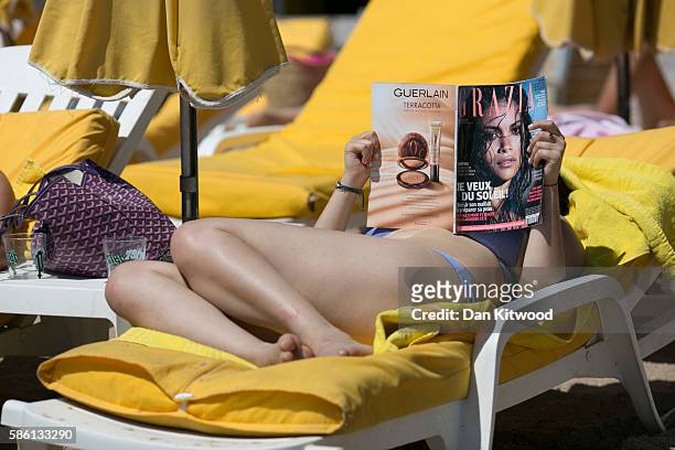 Woman reads a magazine on a sun lounger on August 5, 2016 in Cannes, France. Security along the French Riviera and across France has been stepped up...
