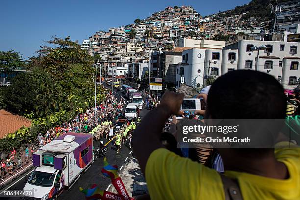 People watch on from the Vidigal 'favela' community as the Olympic torch passes by during the Olympic torch relay on August 5, 2016 in Rio de...