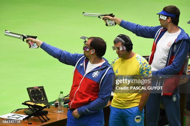 Serbia's Dimitrije Grgic , Ukraine's Oleh Omelchuk and Serbia's Damir Mikec aim for the target during a training session for the 10m air pistol event...