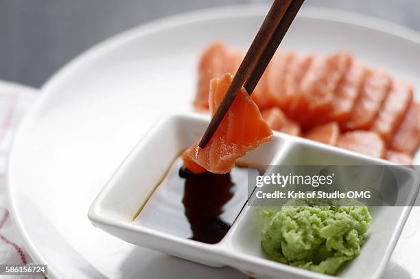 dipping sliced salmon meat in sauce - sauce au soja photos et images de collection