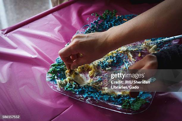 College students dip cookies into a cake to grab some to taste at the Edible Book Festival, April, 2014. Courtesy Eric Chen. .