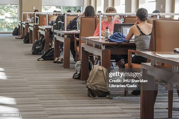 View down the sunny aisle of the Albert Hutzler Reading Room, a two-story silent reading room in the Brody Learning Commons of Johns Hopkins...