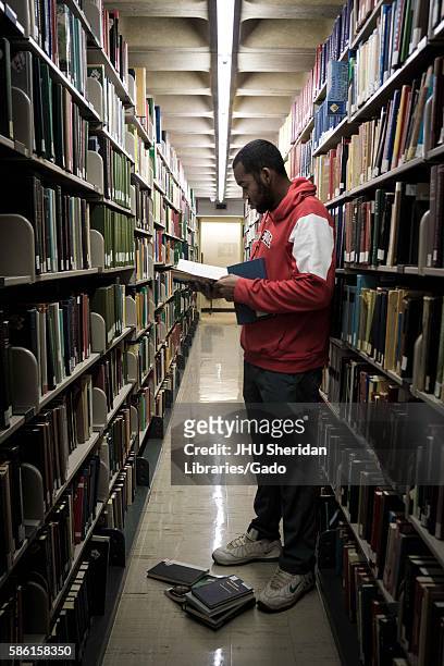 Student stands and reads a book among the stacks in the Milton S. Eisenhower Library on the Homewood campus of the Johns Hopkins University in...