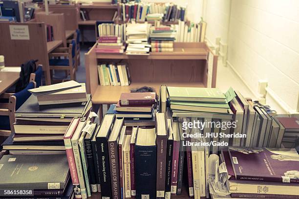 Graduate student sits at his work space, surrounded by piles of books, in the Milton S. Eisenhower Library on the Homewood campus of the Johns...
