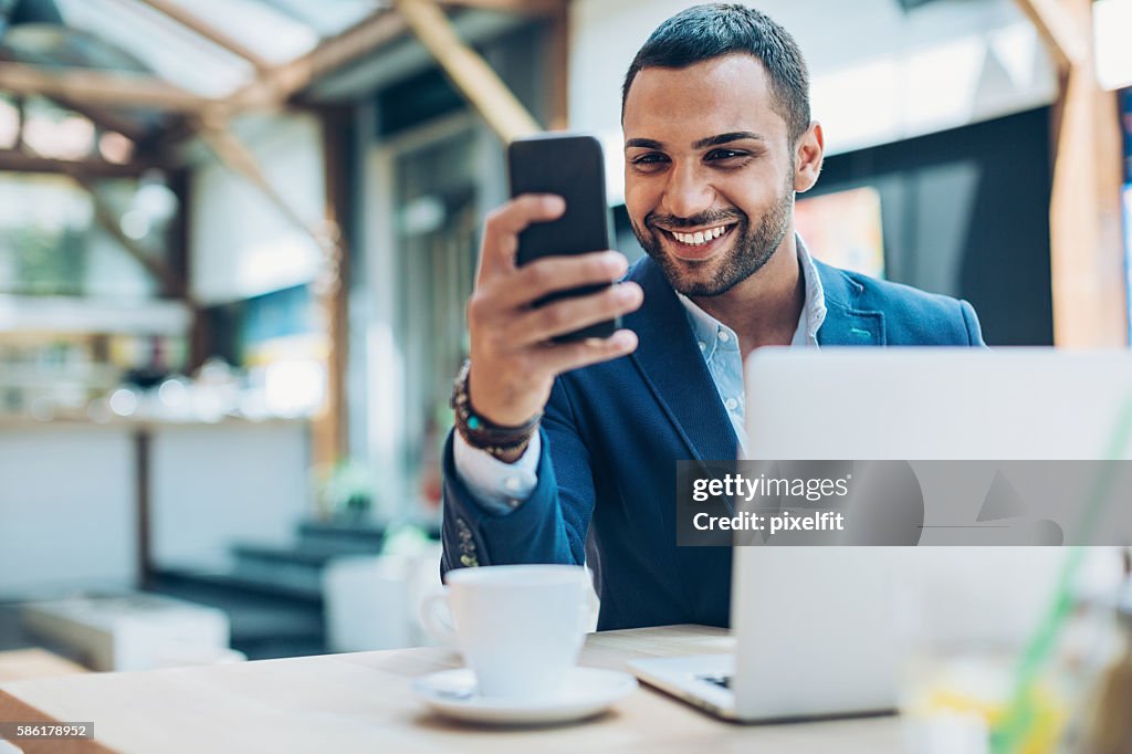 Middle Eastern ethnicity businessman texting in cafe