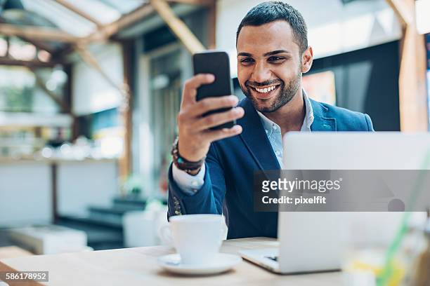 Middle Eastern ethnicity businessman texting in cafe