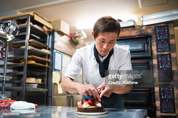 baker decorating a cake - asian man cooking stockfoto's en -beelden