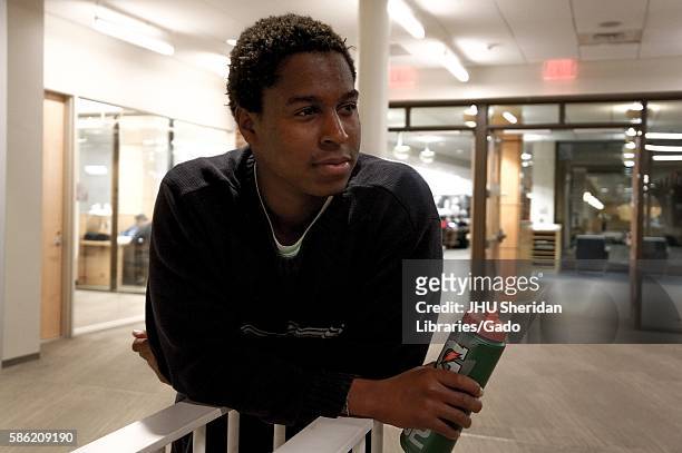 Male student in a black shirt, holding a gatorade bottle, leaning on a stairway of Brody Learning Commons at Johns Hopkins University, 2016. Courtesy...