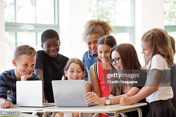 school children using laptop with teacher in the classroom - 5-10 2016 stock pictures, royalty-free photos & images