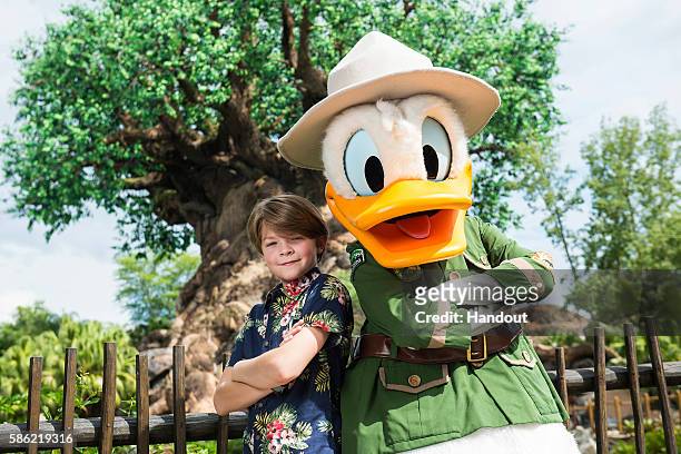 In this handout photo provided by Disney Parks, Disney's "Pete's Dragon" star Oakes Fegley poses with Donald Duck at Disney's Animal Kingdom on...