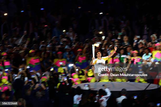 Former tennis player Gustavo Kuerten carries the Olympic Torch during the Opening Ceremony of the Rio 2016 Olympic Games at Maracana Stadium on...