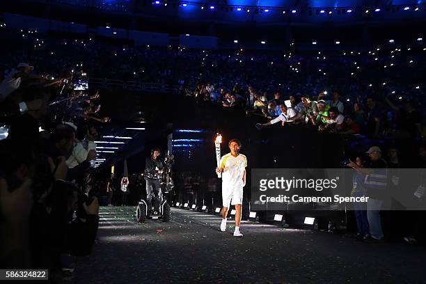Former Brazilian tennis player Gustavo Kuerten carries the Olympic Torch during the Opening Ceremony of the Rio 2016 Olympic Games at Maracana...