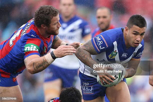 Michael Lichaa of the Bulldogs is tackled by Korbin Sims of the Knights during the round 22 NRL match between the Newcastle Knights and the...