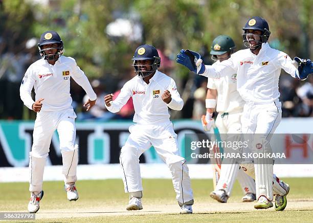 Sri Lankan cricketers Dinesh Chandimal,, Kaushal Silva and Kusal Mendis celebrate the wicket of Australian cricketer David Warner during the third...
