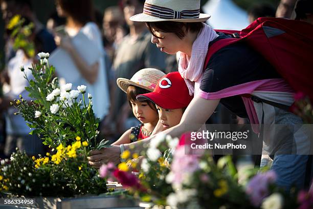 Visitors lays flowers and pray for the atomic bomb victims in front of the cenotaph during the 71st anniversary of the atomic bombing on Hiroshima at...
