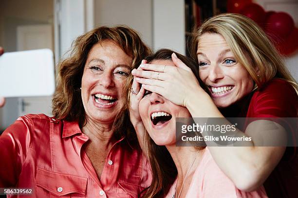 good friends taking a self-portrait with a smartphone at a party - mid adult women stock pictures, royalty-free photos & images