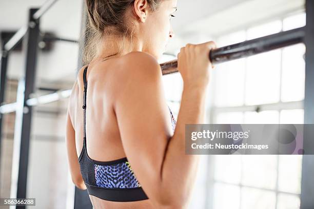 midsection of female exercising on pull-up bar in gym - chin ups stockfoto's en -beelden