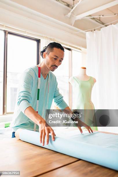 kleidermacher rollen stoff aus - schneiderpuppe stock-fotos und bilder