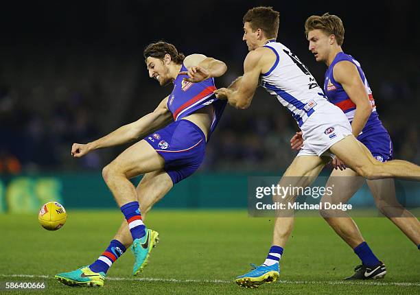 Marcus Bontempelli of the Bulldogs kicks the ball away from Shaun Atley of the Kangaroos during the round 20 AFL match between the Western Bulldogs...