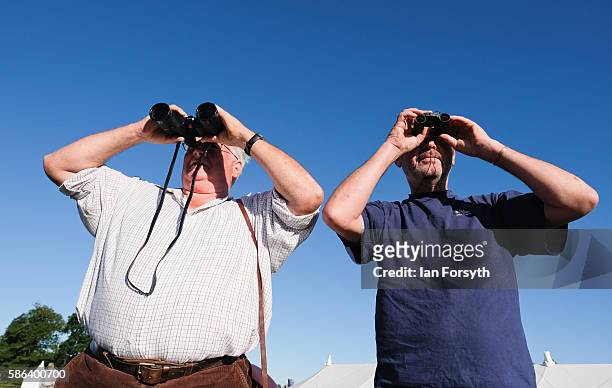 Two men with binoculars watch as a sheepdog drives sheep towards a pen at the British National Sheep Dog Trials on August 6, 2016 in York, England....