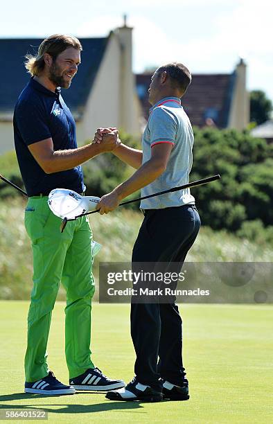 Johan Carlsson of Sweden and Alex Noren of Sweden shake hands on the green of hole 16 after Noren won their match on day three of the Aberdeen Asset...