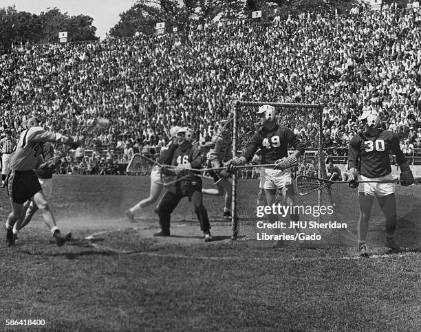 During a men's lacrosse game at Johns Hopkins University, a JHU player reaches to throw a powerful shot while members of the opposing team keep back...