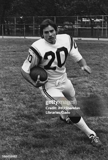 Johns Hopkins University football player in uniform carrying the football in motion on a field at Johns Hopkins University, Baltimore, Maryland,...