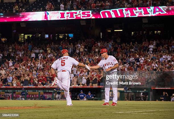 Albert Pujols and third base coach Ron Roenicke of the Los Angeles Angels of Anaheim shake hands as Pujols runs the bases after hitting a three-run...