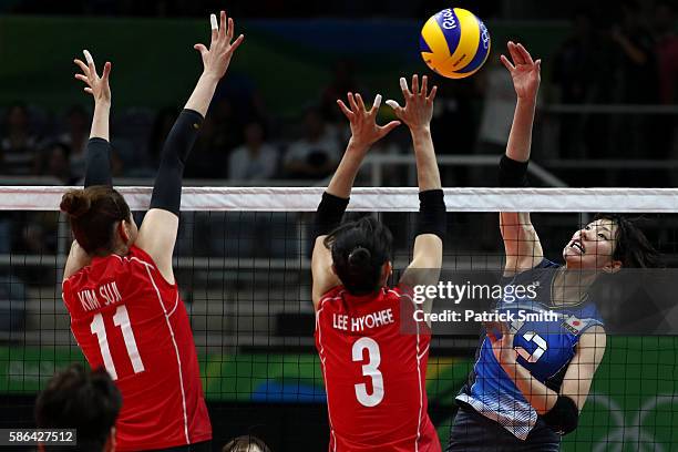 Yuki Ishii of Japan plays a shot in front of Saori Kimura of Korea and Erika Araki of Korea during the Women's Preliminary Pool A match between Japan...