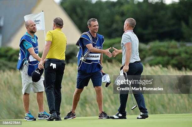 Alex Noren of Sweden and James Morrison of England shake hands with their caddies after Alex Noren won their match on day three of the Aberdeen Asset...