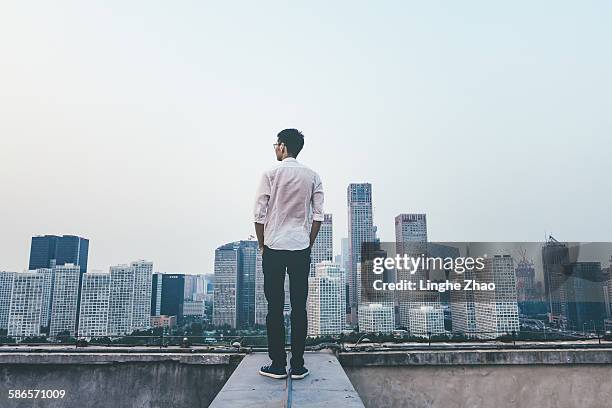 businessman looking at cityscape - rear stockfoto's en -beelden