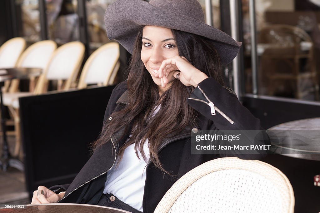 Smiling young woman sitting at a sidewalk cafe.