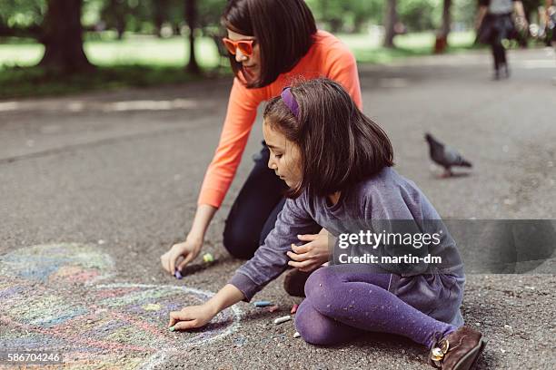 kids drawing with chalk on asphalt - family chalk drawing stock pictures, royalty-free photos & images