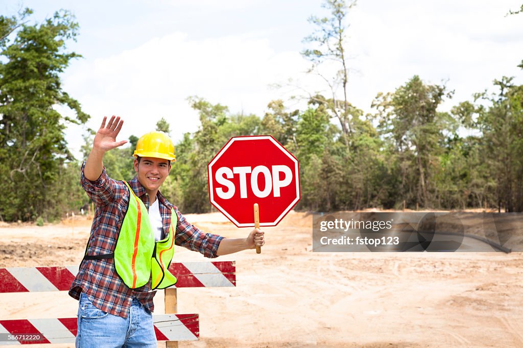 Trabajador de la construcción, signalman sostiene la señal de la parada en el sitio del trabajo.