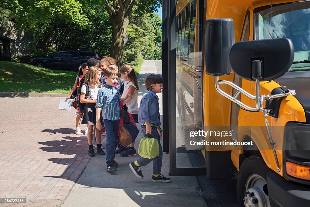 Group of elementary school kids getting in yellow school bus.
