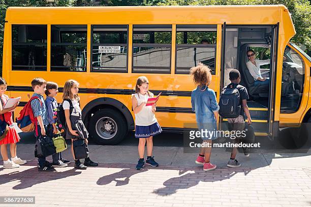 gruppe von grundschulkindern, die in einen gelben schulbus steigen. - boarding a bus stock-fotos und bilder